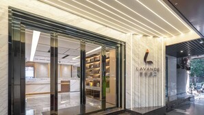 Una entrada de hotel moderna con fachada de vidrio, escalones de mármol y un letrero que dice "LAVANDE".