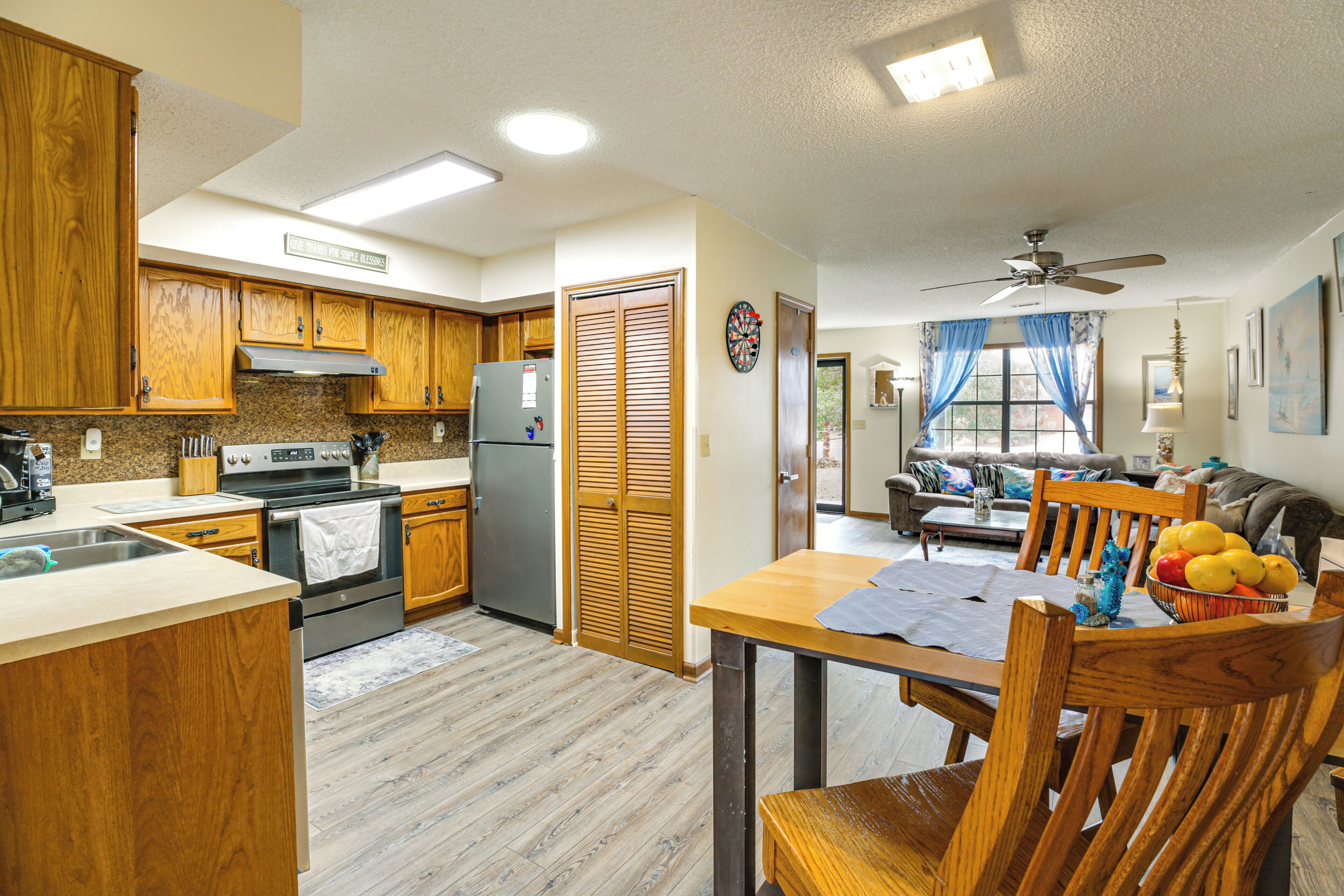 A kitchen with wooden cabinets, a refrigerator, and a dining area with a table and chairs.