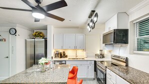 A modern kitchen with white cabinets, a granite countertop, a stainless steel refrigerator, a microwave, and a stove. - Steps to Shore: Walkable Clearwater Beach Condo (Clearwater)