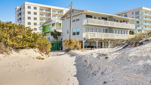 A beachfront hotel with multiple balconies, a sandy beach, and a clear blue sky. - Steps to Shore: Walkable Clearwater Beach Condo (Clearwater)