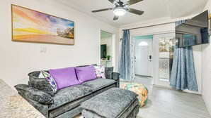A living room with a grey sofa, ottoman, and a ceiling fan. - Steps to Shore: Walkable Clearwater Beach Condo (Clearwater)
