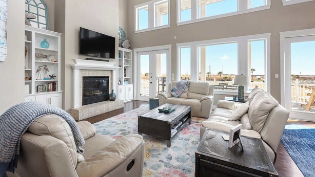 A spacious living room with a fireplace, multiple seating areas, and large windows offering a view of the city.