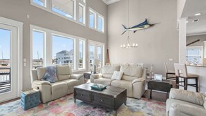A spacious living room with a large window, a sofa, a coffee table, and a chandelier.