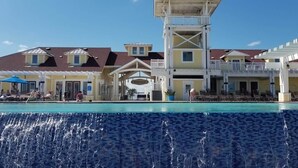 A resort with a pool, a beach club, and a multi-story building with balconies.