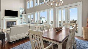 A spacious living room with a fireplace, a large TV, and a dining area with a wooden table and chairs.
