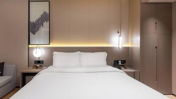A modern hotel room with a large bed, bedside tables, a desk, and a wardrobe.