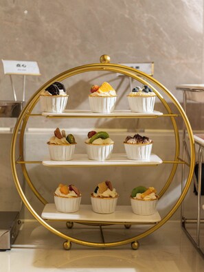 Une présentation de desserts comprenant divers cupcakes et pâtisseries, disposés sur un présentoir à bordure dorée.