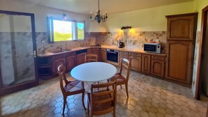 Una cocina con una mesa redonda de comedor, armarios de madera, un microondas y una araña.