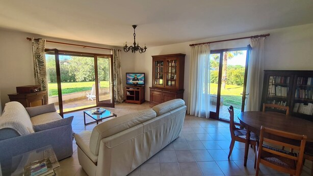 Un salón amplio con sofá, televisor, aparador y mesa de comedor.