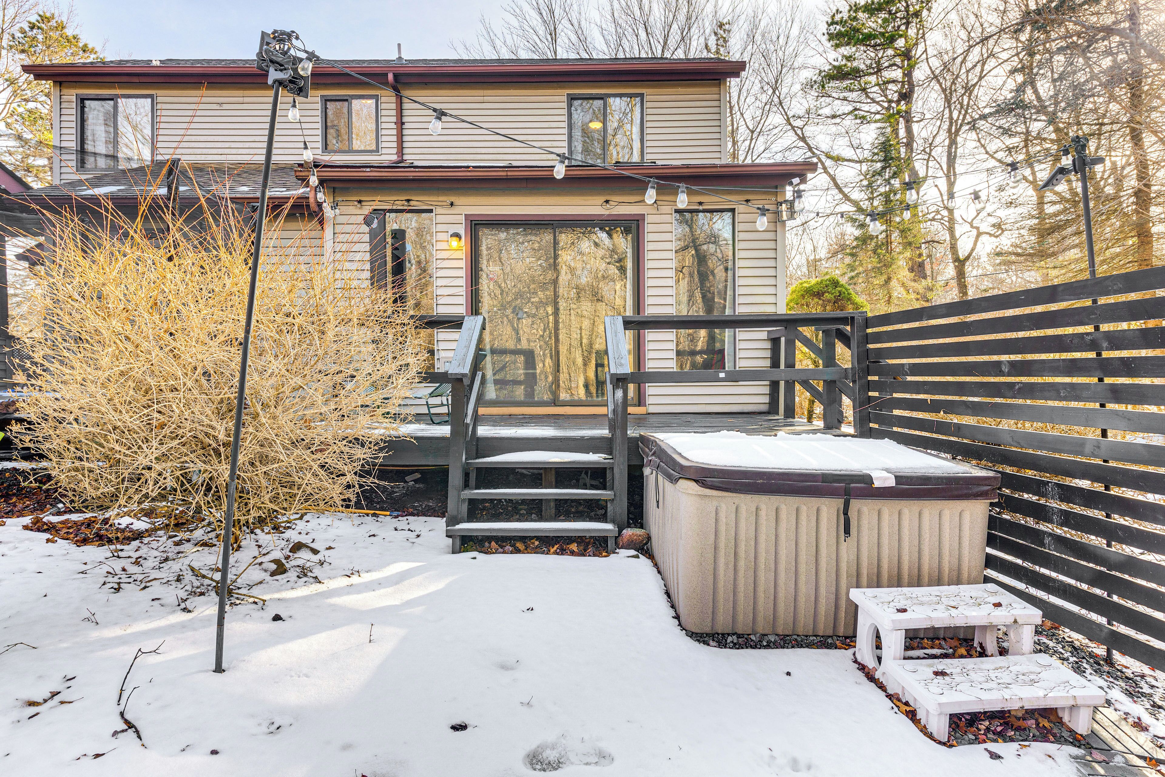 A house with a covered porch, a hot tub, and a wooden fence.