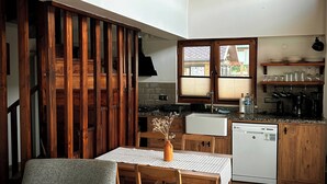 A modern kitchen with wooden accents, a dining area with a table and chairs, and a staircase leading to an upper level. - Abant Cozy Homes (Bolu)