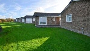 A row of brick houses with large windows and a well-maintained lawn. - Brambles Farm Bungalow (Freshwater)