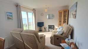 A living room with a sofa, a television, and a cabinet. - Brambles Farm Bungalow (Freshwater)