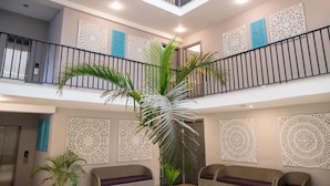 A multi-level interior with a central staircase, decorative wall panels, and seating areas. - 30 Vamsor Heights (Gurugram)