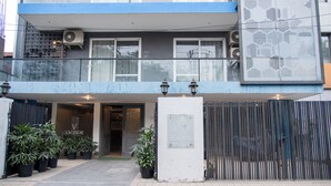 A building with a gated entrance, potted plants, and a sign indicating 'VAMSOR 30, Sector 56'. - 30 Vamsor Heights (Gurugram)