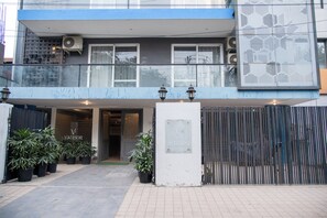 Stunning building with a balcony offering a view of the street below, surrounded by lush greenery and a modern architectural design.
