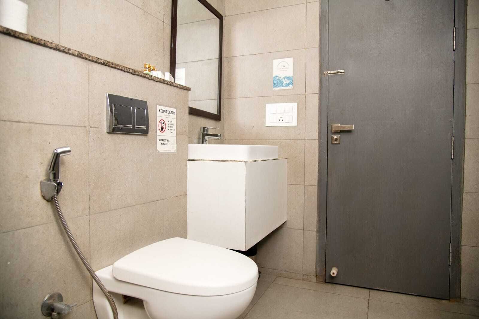 A bathroom with a toilet, a sink, a shower, and a door.
