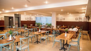A spacious dining area with multiple wooden tables and light blue chairs, featuring ceiling fans and recessed lighting. - 30 Vamsor Heights (Gurugram)
