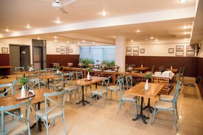 Enjoy a communal dining experience in our elegant dining area, featuring beautifully set tables and artwork-adorned walls.