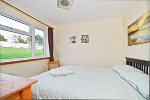 Enjoy a serene view of the surrounding landscape from the large window in this stylish room, featuring a comfortable bed and a selection of artwork.