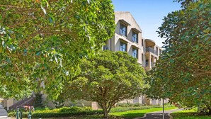 Un immeuble résidentiel au style architectural moderne, doté de nombreux balcons et de grandes fenêtres.