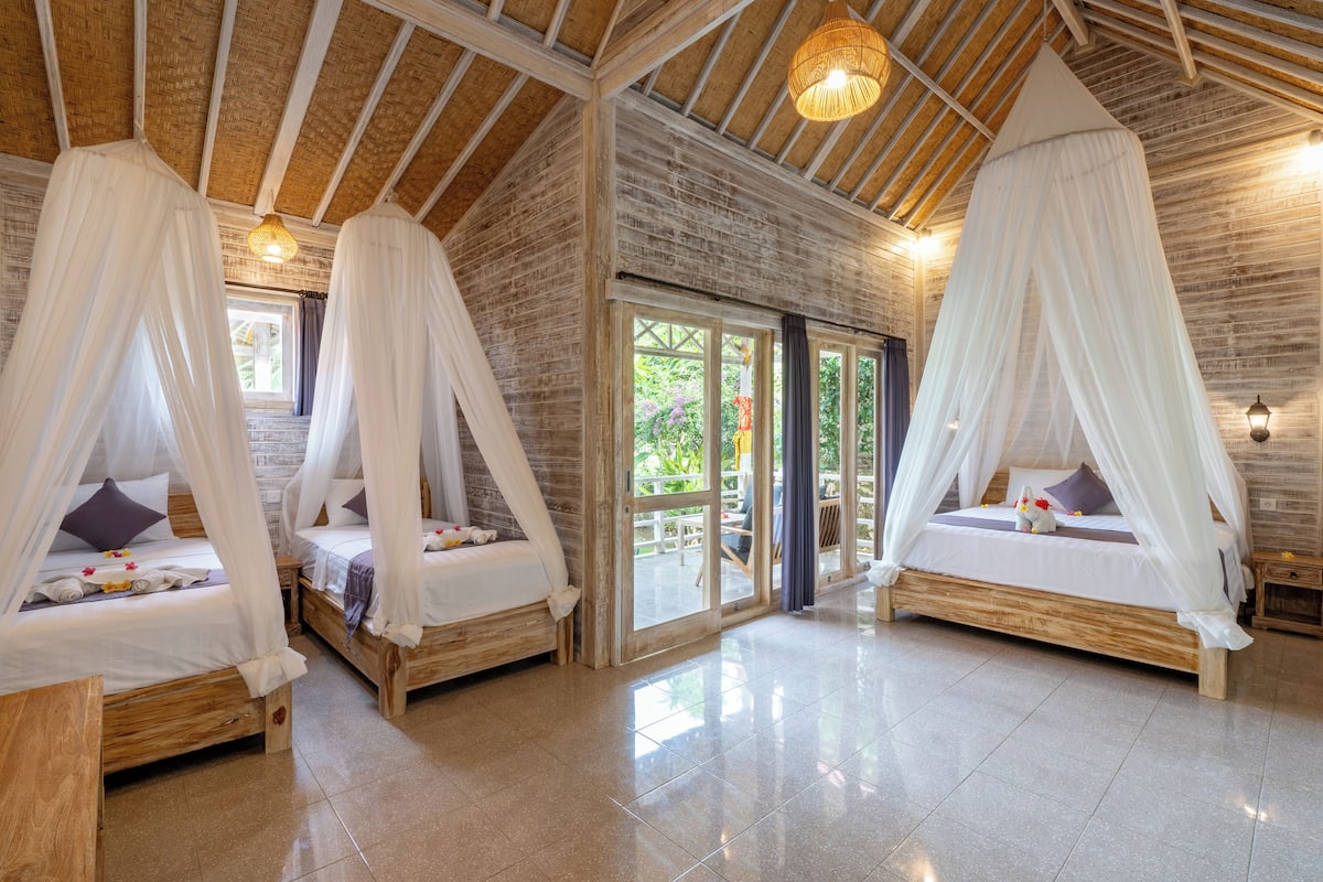 Une chambre dotée de deux lits, chacun surmonté d’un baldaquin, avec un plancher en bois et une vue sur l’extérieur.