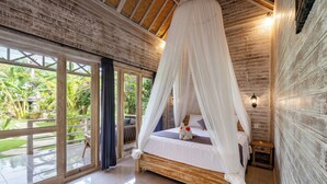 A room with a wooden bed, white canopy, large windows, and a view of greenery outside. - Le Biu Garden View (Lembongan Island)