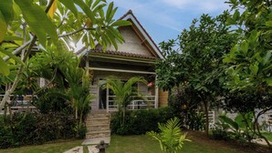 A house with a tiled roof, surrounded by lush greenery and a stone pathway leading to the entrance. - Le Biu Garden View (Lembongan Island)
