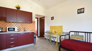 A compact living space with a kitchenette, a dining area, and a bed. - Residence Sole - Apartment 1 (Tertenia)