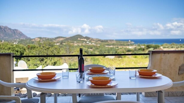 A table set with bowls and a bottle, overlooking a scenic landscape. - Residence Sole - Apartment 1 (Tertenia)