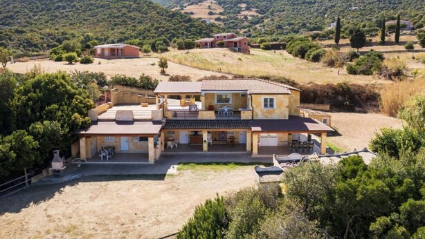 Une grande maison à deux étages, dotée d’un patio et d’un petit jardin.