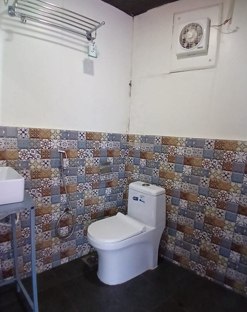 Une salle de bain avec des toilettes, une douche et un mur carrelé.
