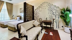 Een hotelkamer met twee bedden, een bank, een tafel en een decoratieve wand.