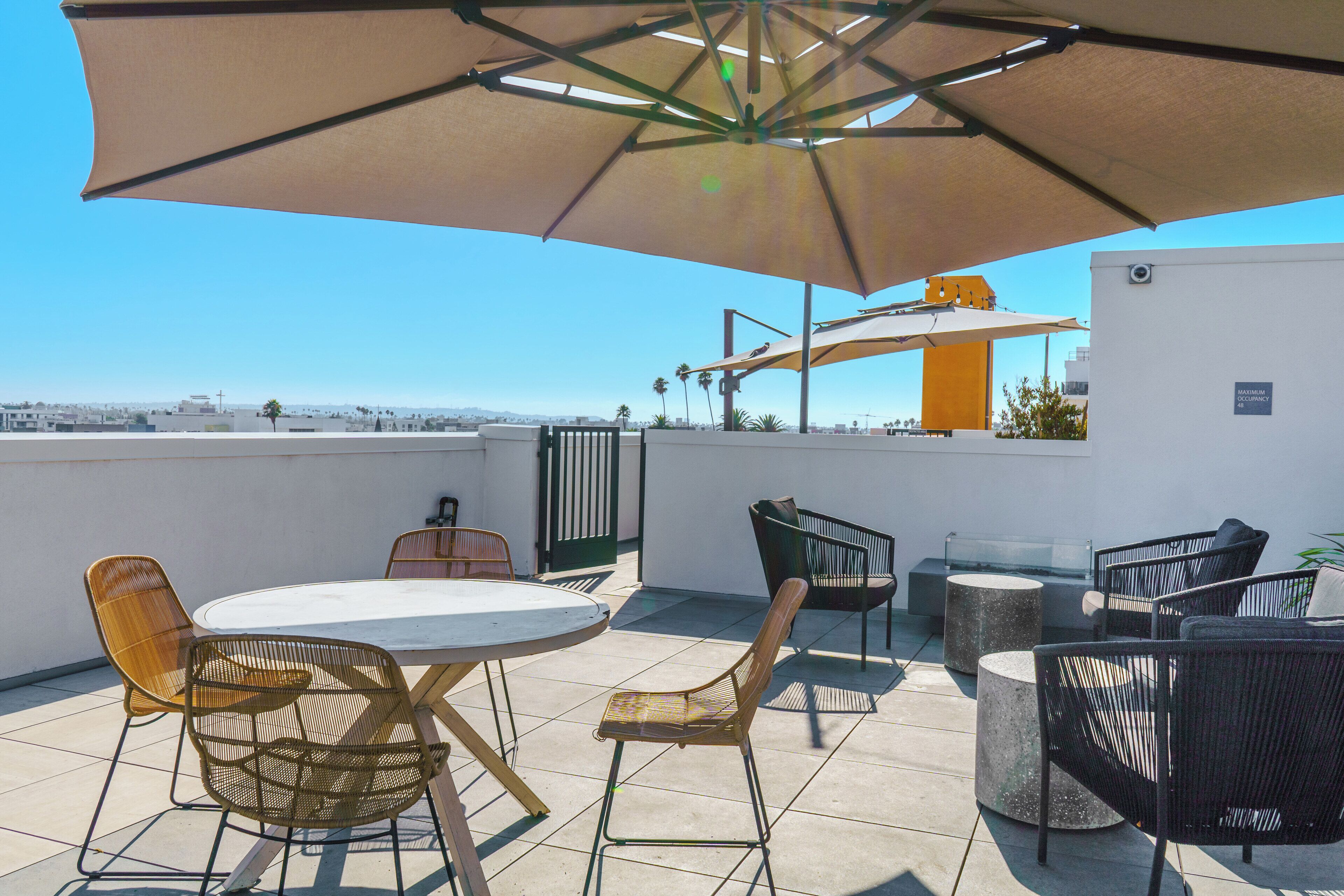An outdoor patio with a round table, chairs, and a large umbrella.