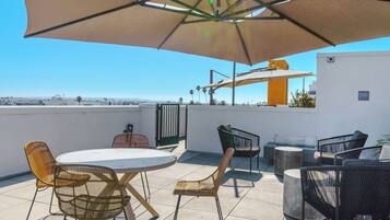 An outdoor patio with a round table, chairs, and a large umbrella.