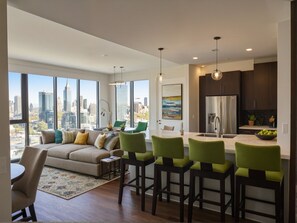 Una sala moderna con un sofá, sillones y vista a la ciudad.