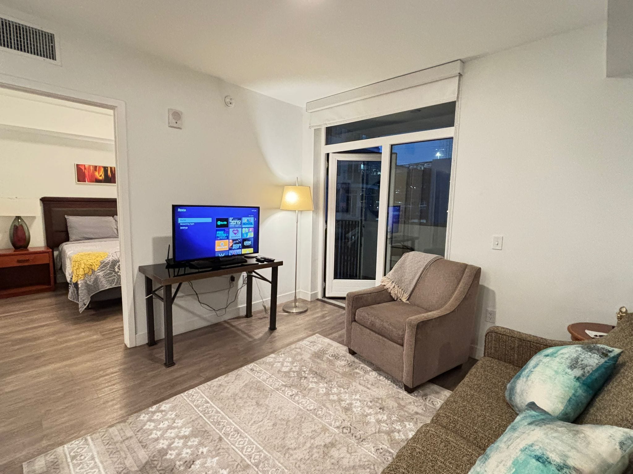 A living room with a television on a stand, a sofa, a chair, and a patterned rug.