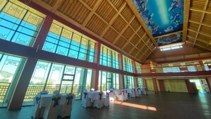 A spacious hall with high ceilings and large windows, featuring traditional wooden beams and a mural on the ceiling. - Secret of the Silk Road (Kharkhorin)