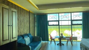 A room with a sofa, a table with chairs, a window with a view of greenery, and a cabinet. - Secret of the Silk Road (Kharkhorin)