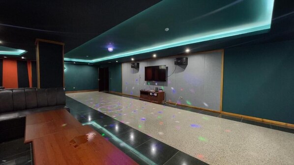 A spacious lobby with a long counter, a television mounted on the wall, and a seating area with a dark-colored sofa.
