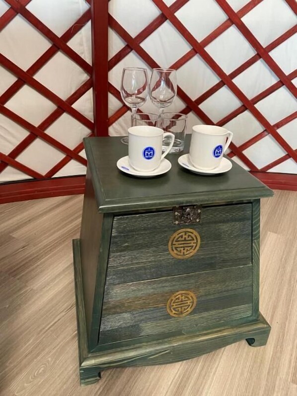 A small wooden chest with two white cups and saucers on top, featuring a traditional design with two circular symbols on the front.