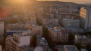 A cityscape with a prominent building featuring a large central dome, surrounded by other buildings with varied architectural styles. - View of the Old City (Jerusalem)