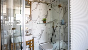 A modern bathroom with a glass shower enclosure, marble walls, and a white toilet. - View of the Old City (Jerusalem)