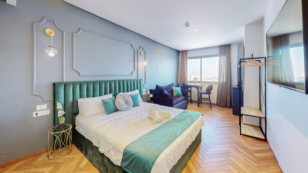 A hotel room with a large bed, a sofa, a small table, and a mirror. - View of the Old City (Jerusalem)