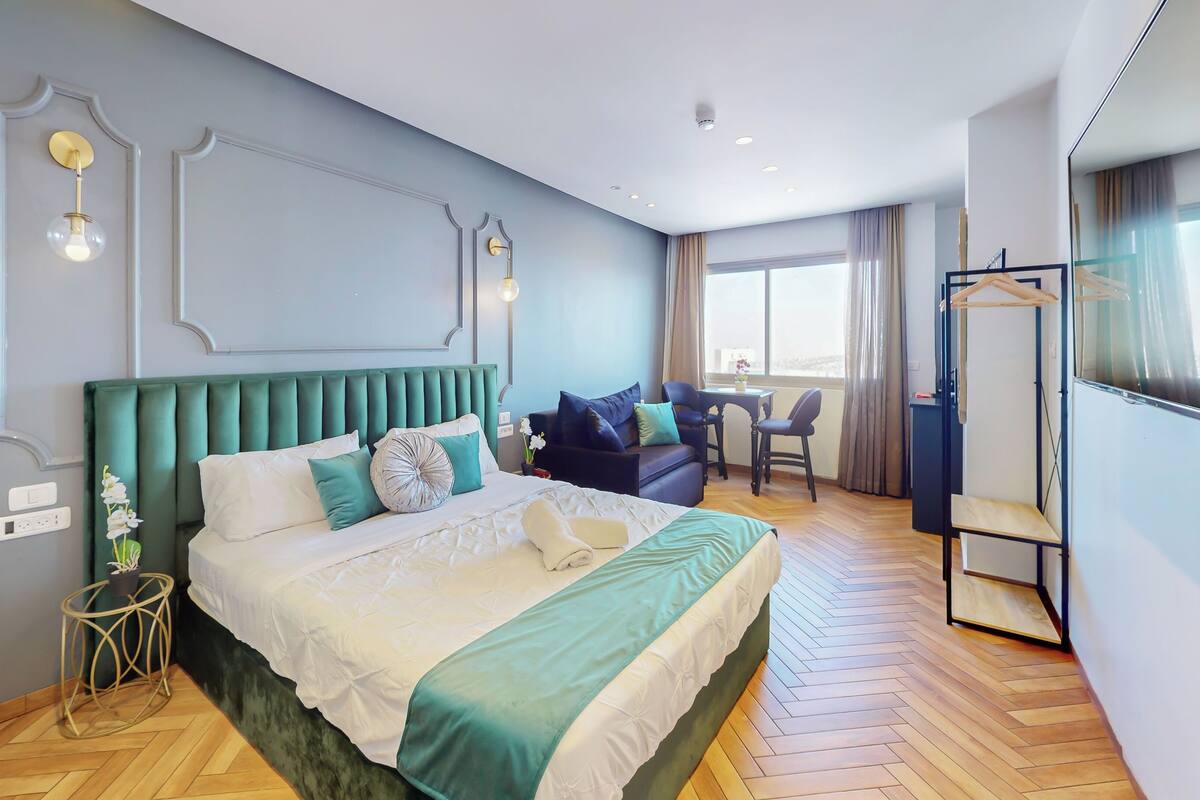 Une chambre d’hôtel avec un grand lit, un canapé, une petite table et un miroir.