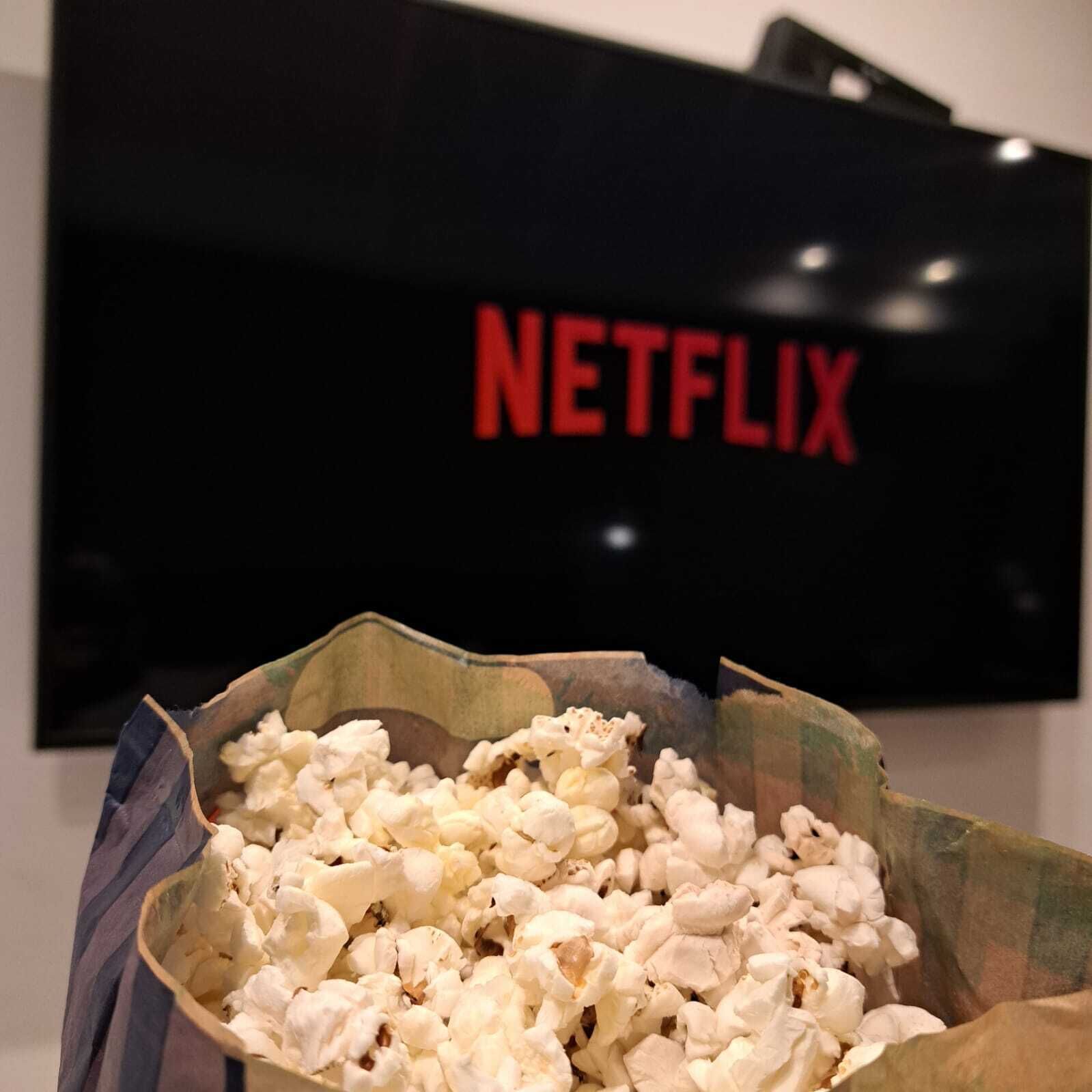 Un ciotola di popcorn davanti a un televisore con il logo Netflix.