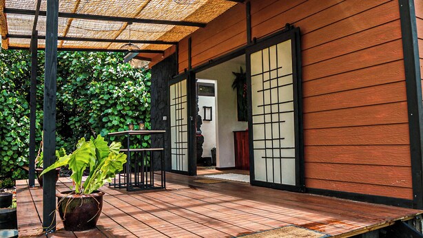 A wooden deck with a pergola, a potted plant, and a traditional Japanese sliding door.