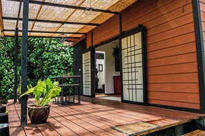 A wooden deck with a pergola, a potted plant, and a traditional Japanese sliding door. - Petit Fare on Tahaa (Tahaa)