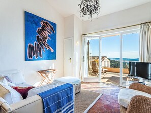 A spacious living room with a large painting, a sofa, a coffee table, and a TV.