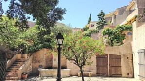 Ein Innenhof mit einer Straßenlaterne, einer Bank, einem kleinen Baum mit rosa Blüten und einer Treppe zu einem Gebäude.